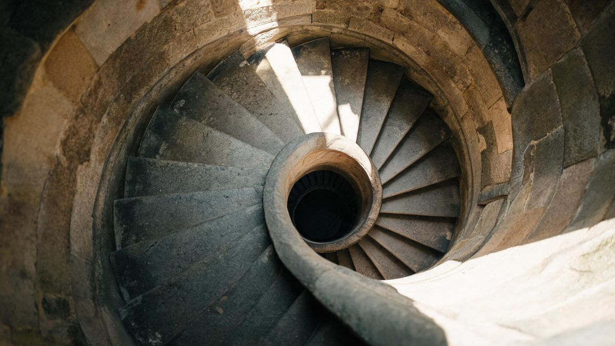A spiral staircase seen from above in raking light, geometric.