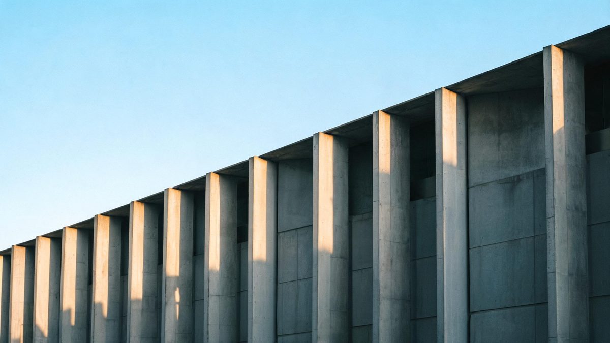 A concrete facade with strong vertical lines in side light, clear sky.