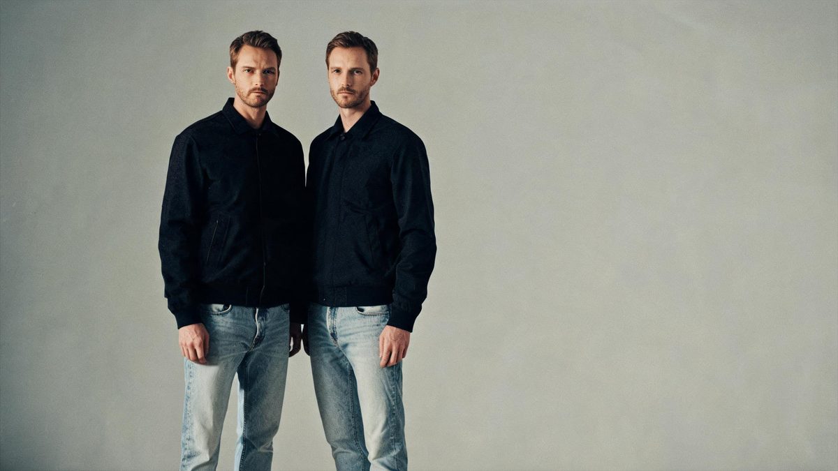 A man with European features standing beside an identical copy of himself, neutral seamless background
