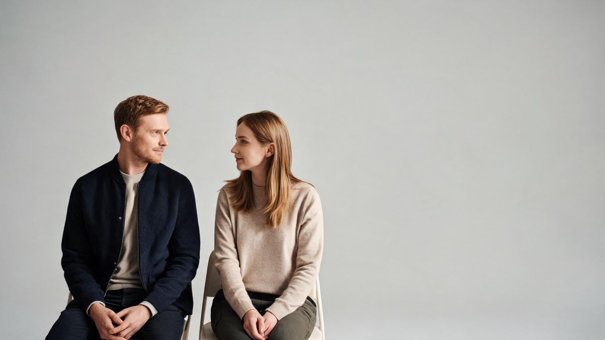 Two people seated side by side in even studio light, gentle eye contact.