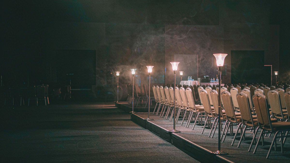 An event venue at setup time with rows of chairs and warm bar lighting