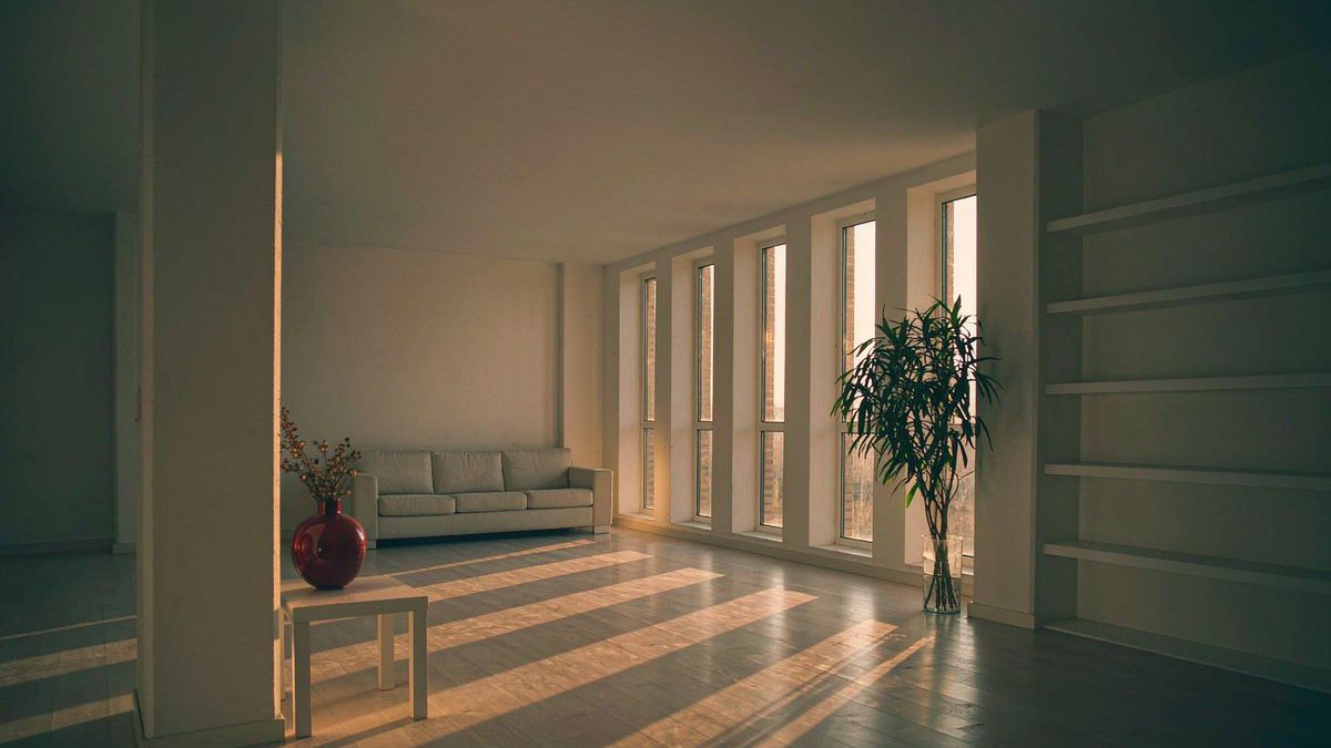 A bright empty living room at golden hour with light across a wood floor