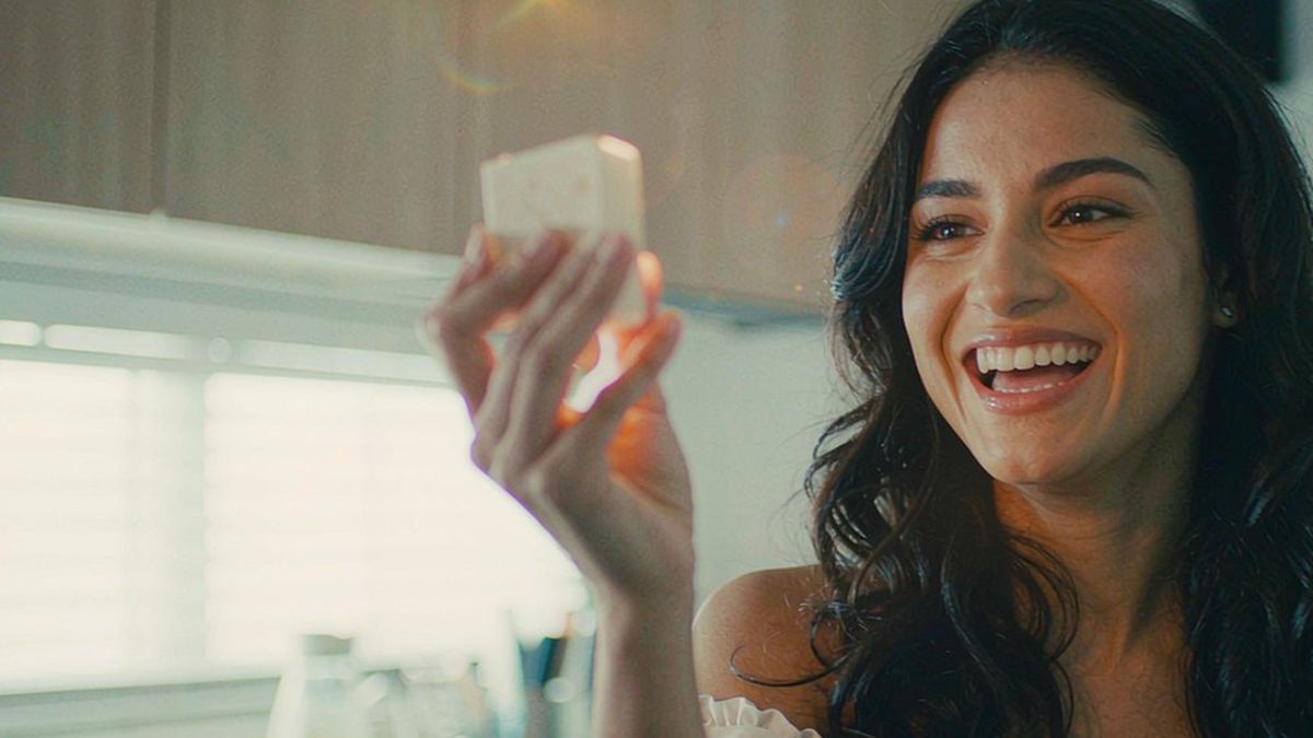 A woman filming a small product at home in natural window light