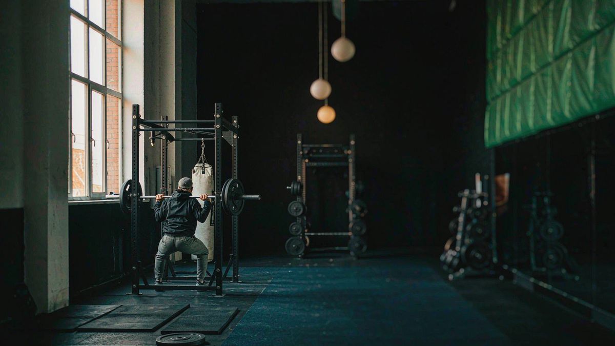 An athlete mid-set on a squat rack in an industrial gym at dawn