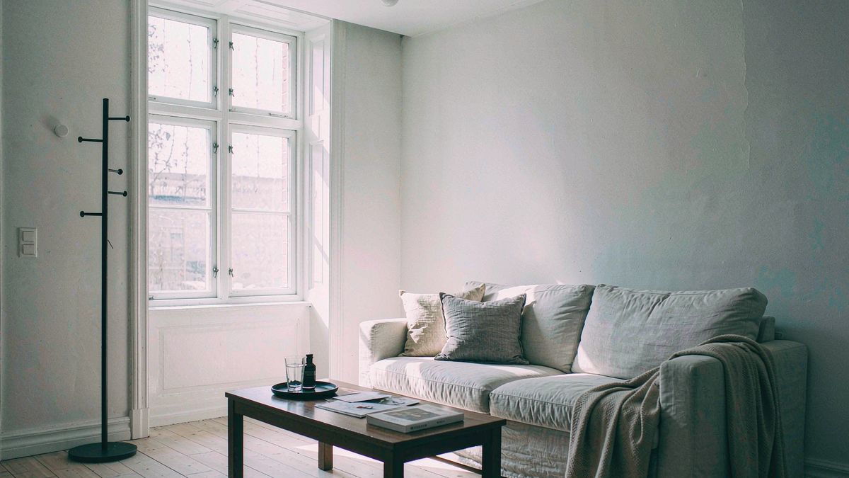 A linen sofa and low table in an empty room with long afternoon shadows