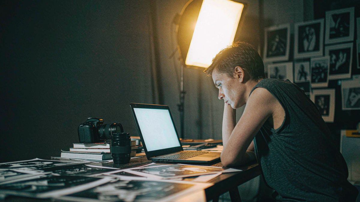 A photographer reviewing images on a laptop in a dim studio
