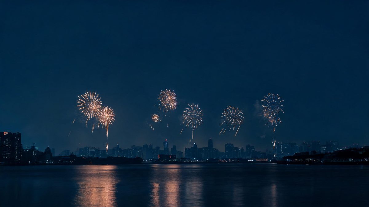 City skyline at midnight on New Year's Eve with fireworks over dark water