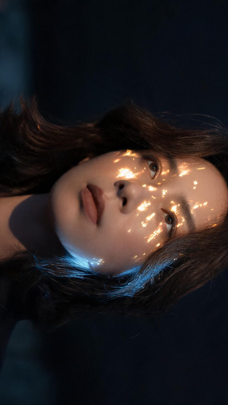 Close-up portrait lit by fireworks, cool blue rim light with warm gold highlights