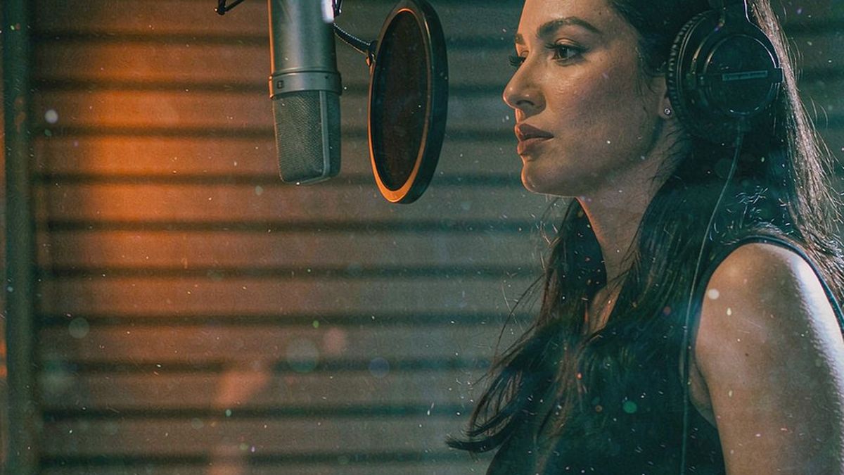 A woman wearing headphones beside a studio microphone