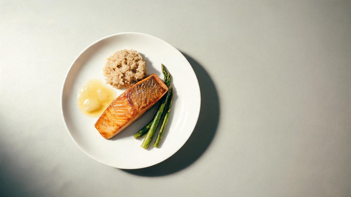 A plated meal photographed from above with soft directional light and shallow focus, broken apart at the moment of the cut
