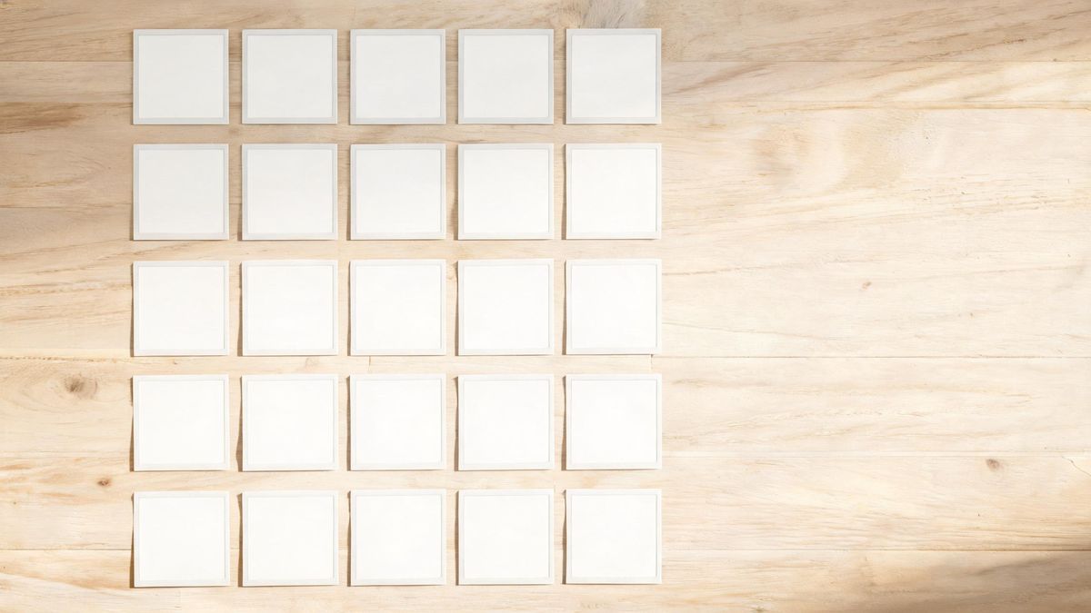 Neat ordered rows of small square prints on a pale wooden table seen from directly above