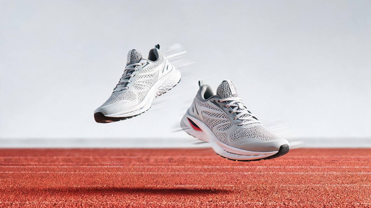 A pair of running shoes caught mid-air above a running track