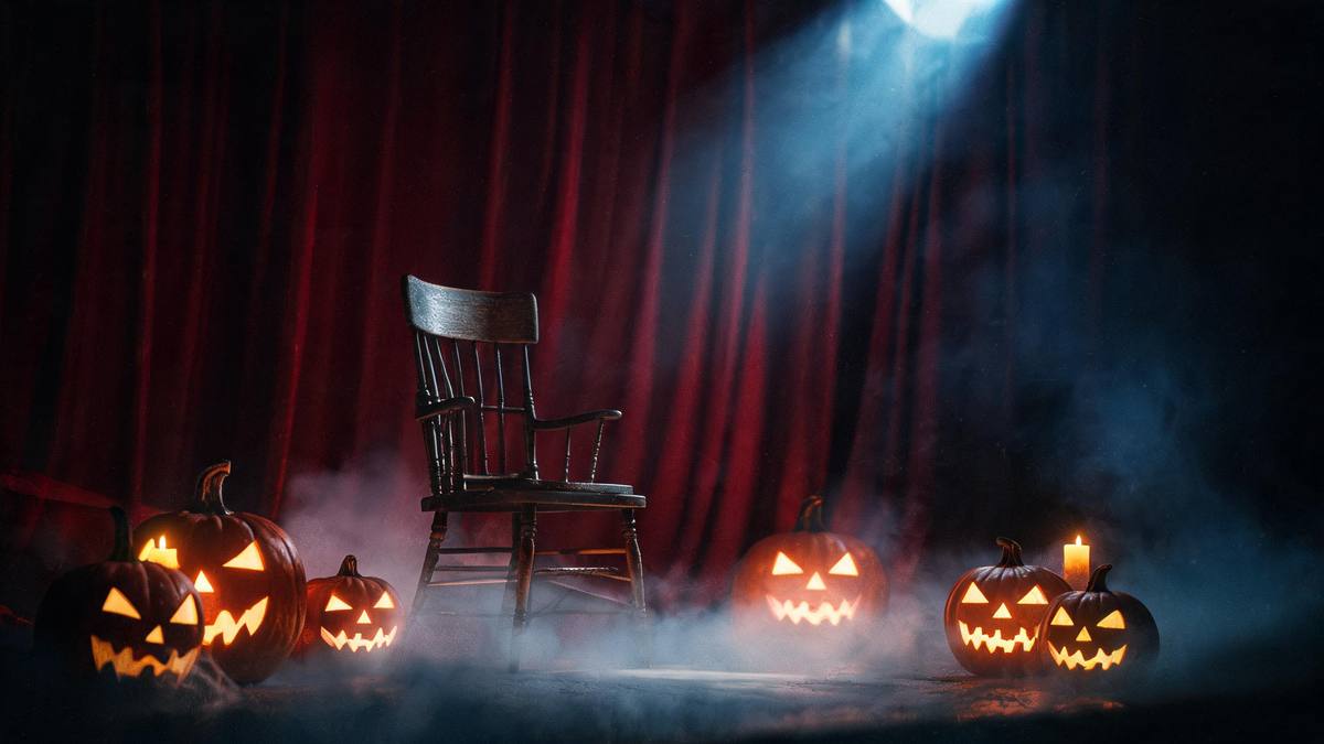 An empty wooden chair under one spotlight in front of a deep crimson curtain