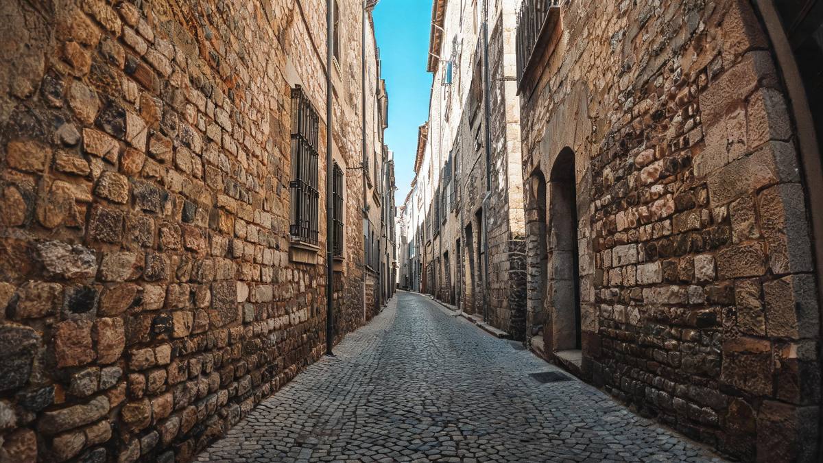 An empty narrow alley shot with a fisheye lens, walls curving inward and a bright sky strip above