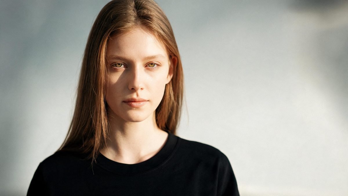 A a single person, front-facing on a plain surface, lit from one side with soft shadow, broken apart at the moment of the cut