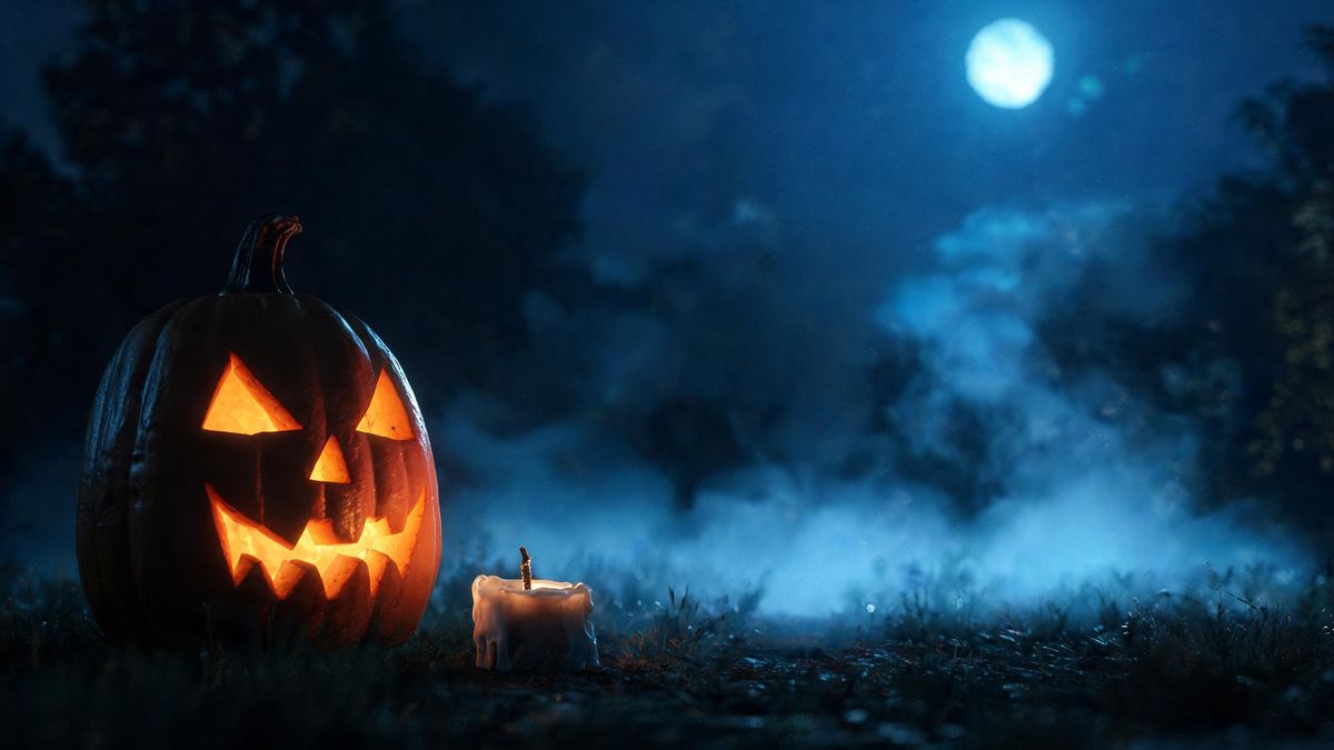 One carved pumpkin beside a burnt-down candle, warm light against deep shadow