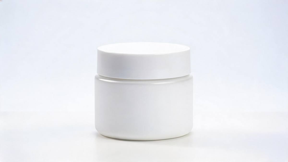 A plain white cosmetic jar on a pale seamless surface in diffused light