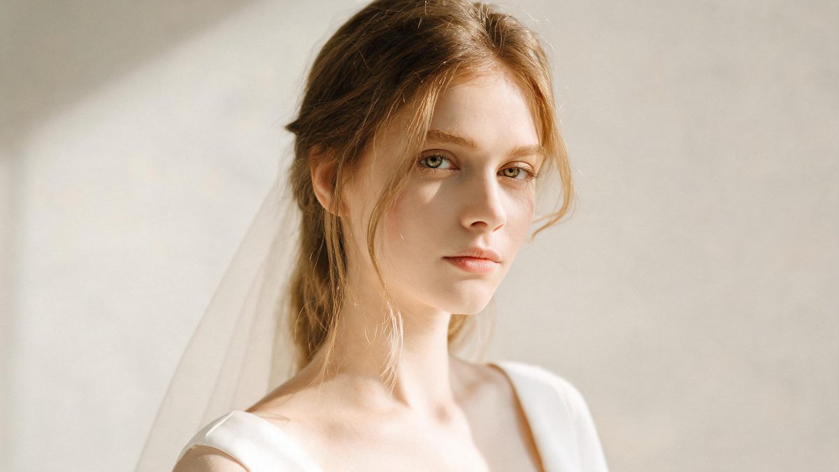 A a bride in a wedding dress on a plain surface, lit from one side with soft shadow, broken apart at the moment of the cut