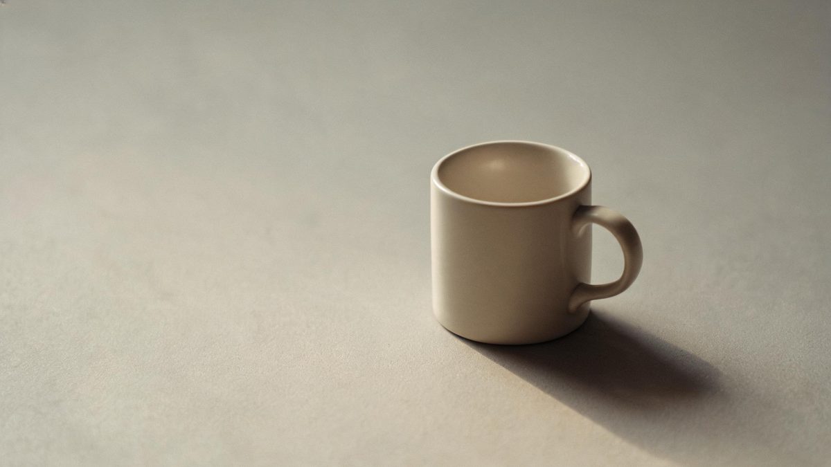 A single everyday object on a plain surface, lit from one side, broken apart at the moment of the cut