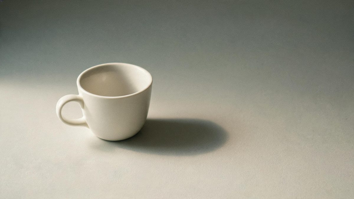 A single everyday object on a plain surface, lit from one side, broken apart at the moment of the cut