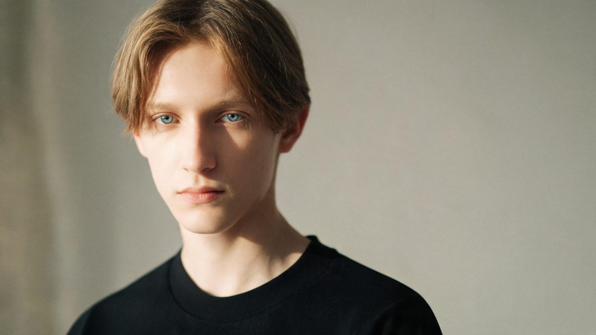 A a single person, front-facing on a plain surface, lit from one side with soft shadow, broken apart at the moment of the cut
