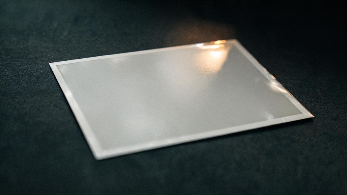 Close-up of a glossy printed photograph catching a reflection at a low angle, faint fingerprints on the surface