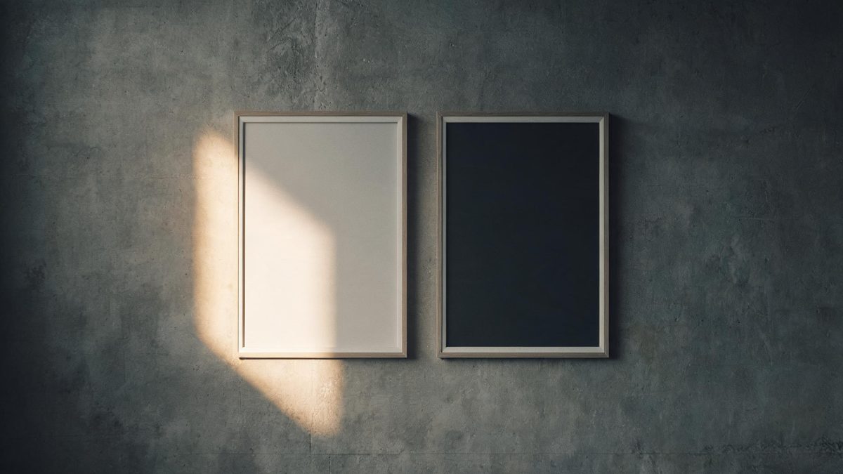 Two identical empty picture frames hanging side by side on a concrete wall